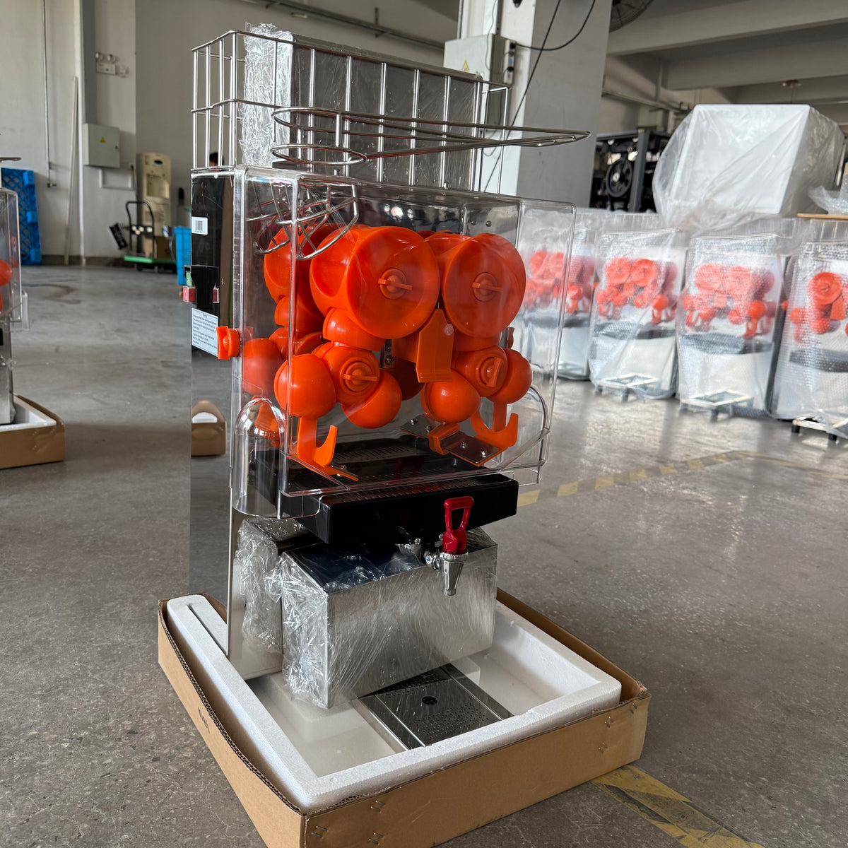 Angled view of BKN-2000EH automatic orange juicer showing stainless steel base and juice outlet